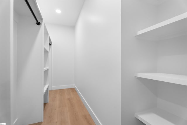 walk in closet with light wood-style flooring