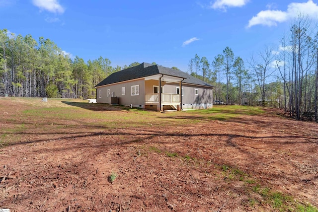 view of side of property with crawl space, a shingled roof, and a yard