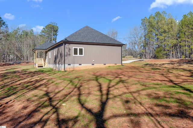 view of side of home featuring crawl space, roof with shingles, and a lawn