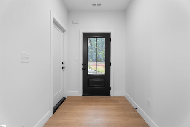 doorway to outside with light wood finished floors, visible vents, and baseboards