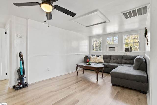 living area featuring baseboards, light wood finished floors, visible vents, and attic access