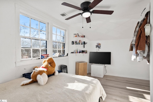 bedroom with visible vents, baseboards, lofted ceiling, light wood-style flooring, and ceiling fan