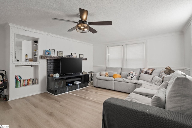 living room with ornamental molding, light wood-style flooring, a textured ceiling, and a ceiling fan