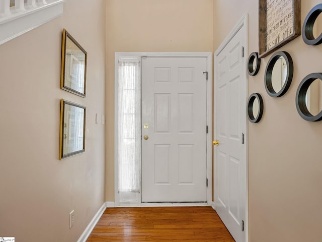 foyer entrance with a wealth of natural light, baseboards, and wood finished floors