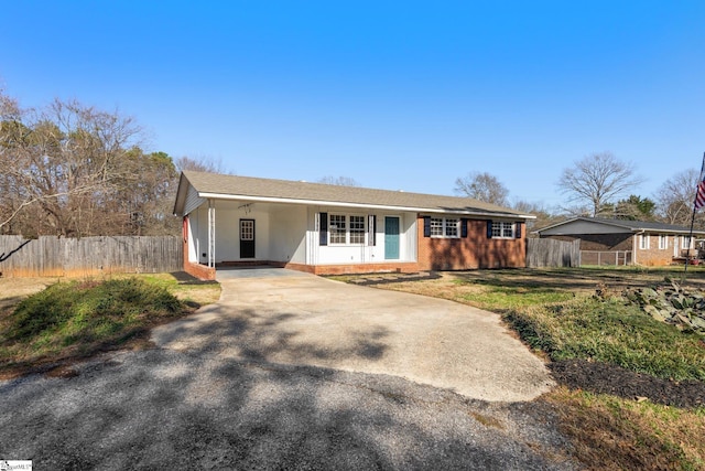 ranch-style house featuring fence, concrete driveway, and brick siding