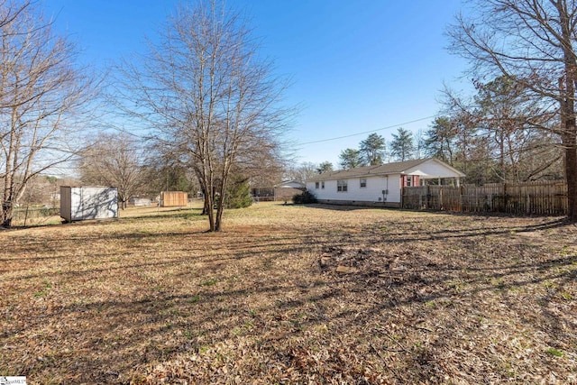 view of yard with a storage shed, fence, and an outdoor structure