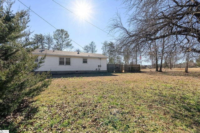 rear view of house featuring crawl space, a yard, and fence