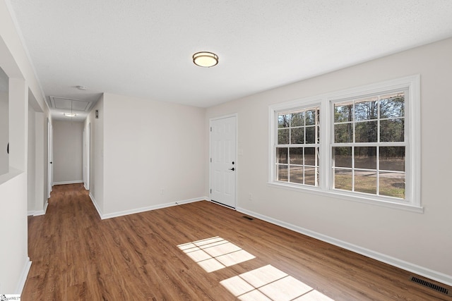 interior space featuring attic access, visible vents, baseboards, and wood finished floors