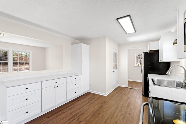 kitchen featuring appliances with stainless steel finishes, dark wood-style flooring, a sink, and white cabinets