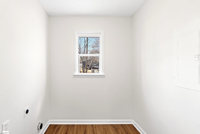 empty room with electric panel, baseboards, and wood finished floors