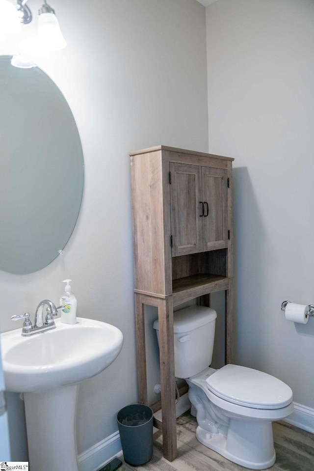 bathroom with toilet, baseboards, a sink, and wood finished floors