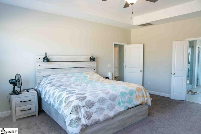 carpeted bedroom featuring a ceiling fan, a raised ceiling, visible vents, and baseboards