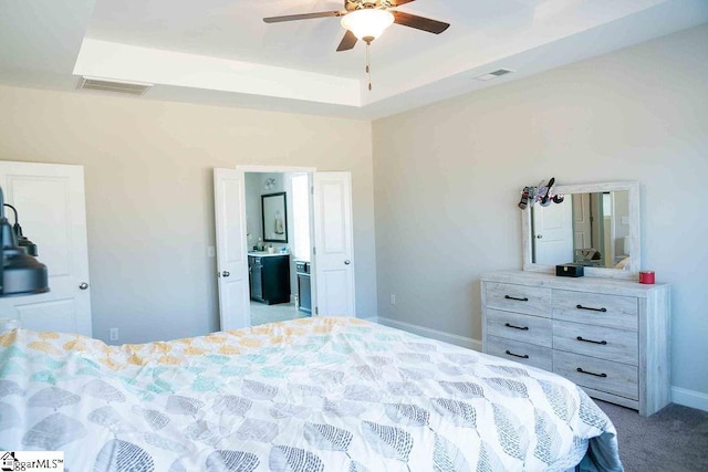 bedroom with light carpet, a tray ceiling, visible vents, and baseboards