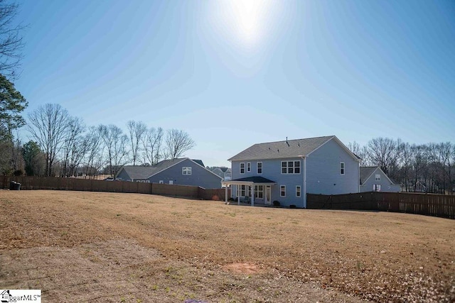 back of property with a fenced backyard and a yard