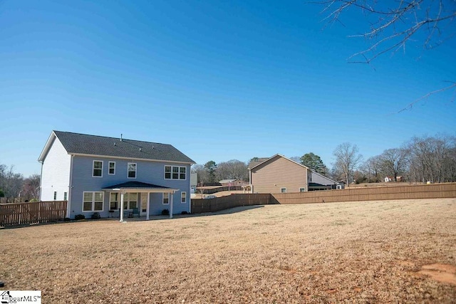 back of property with a fenced backyard and a lawn