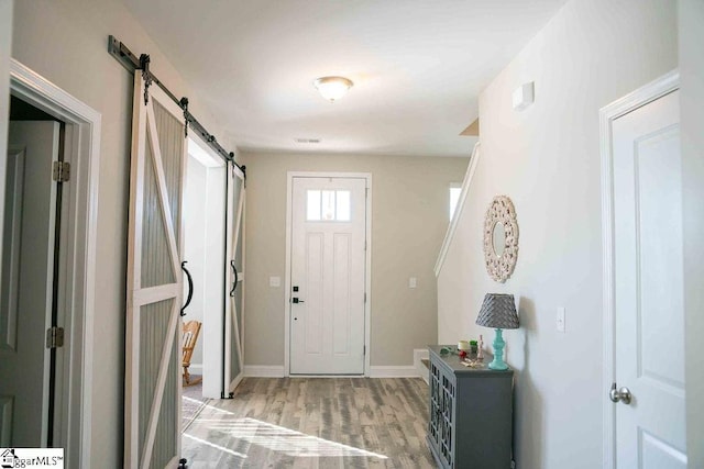 entryway featuring baseboards, a barn door, visible vents, and light wood-style floors