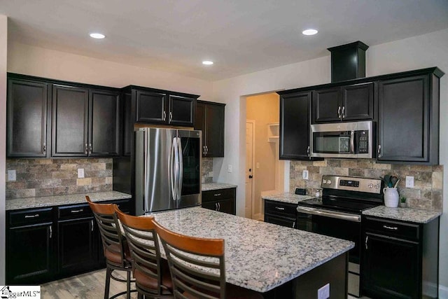 kitchen featuring dark cabinets, stainless steel appliances, a breakfast bar area, and a center island