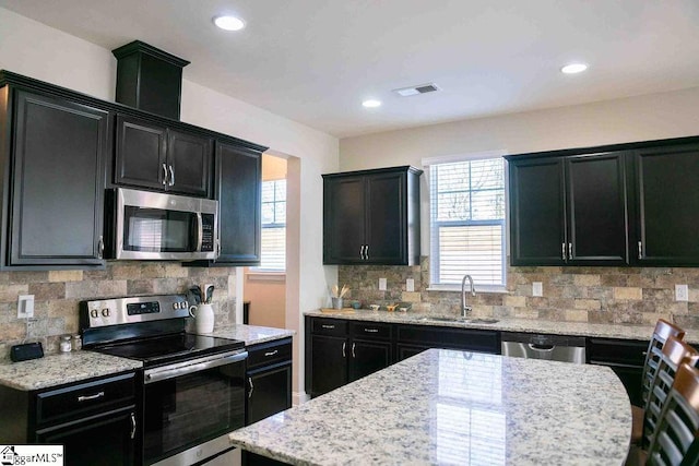 kitchen with visible vents, decorative backsplash, appliances with stainless steel finishes, a sink, and dark cabinets