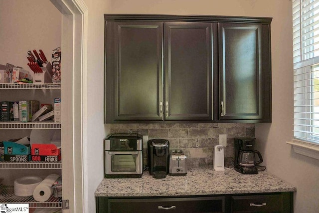 interior space with light stone counters, backsplash, and dark brown cabinetry