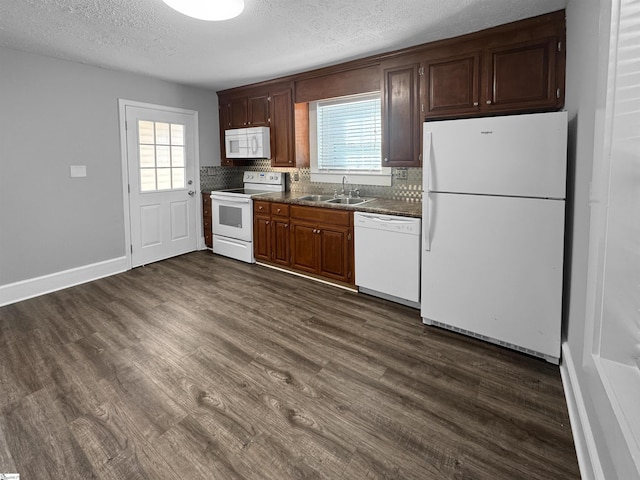 kitchen featuring white appliances, plenty of natural light, dark wood finished floors, and a sink