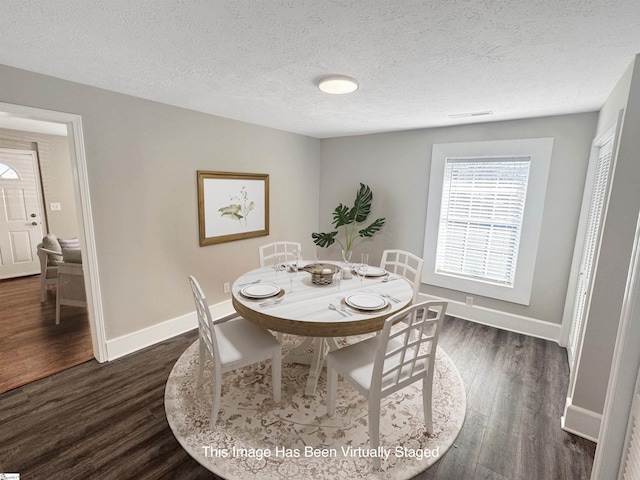 dining room with a textured ceiling, dark wood-style flooring, and baseboards