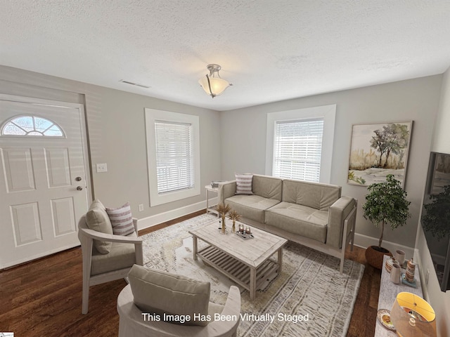 living room with dark wood-style flooring, visible vents, a textured ceiling, and baseboards