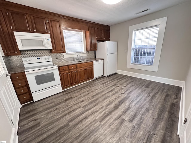 kitchen featuring dark wood-style floors, white appliances, a sink, and a healthy amount of sunlight