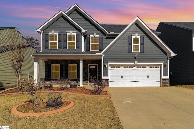 view of front of home featuring a porch, a front yard, stone siding, and driveway