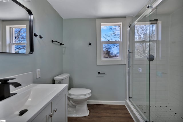 full bath with a stall shower, baseboards, toilet, wood finished floors, and vanity