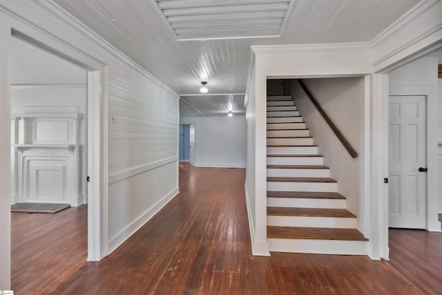 stairway with crown molding and wood finished floors