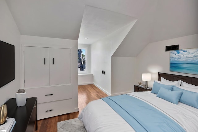 bedroom with baseboards, vaulted ceiling, and dark wood-style flooring