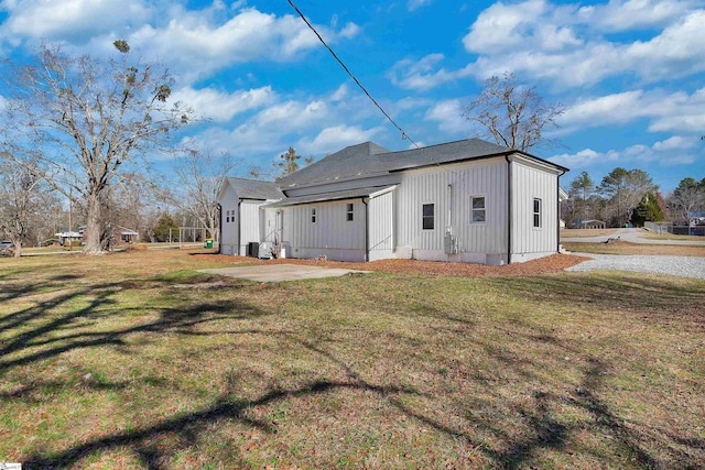 back of house with board and batten siding and a lawn