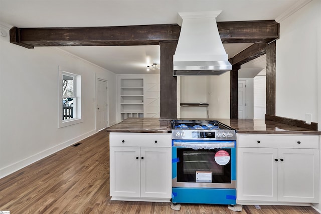 kitchen with premium range hood, dark countertops, gas range, and white cabinets