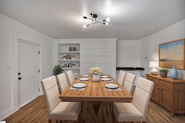 dining space featuring built in features, ornamental molding, and wood finished floors