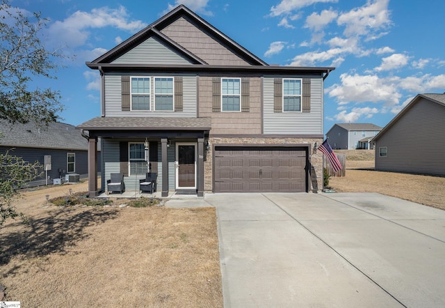 view of front facade featuring central air condition unit, covered porch, concrete driveway, an attached garage, and stone siding