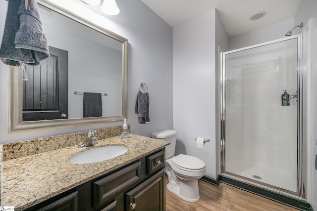 full bath with toilet, wood finished floors, vanity, and a shower stall