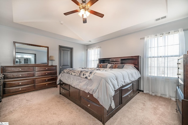 bedroom featuring a ceiling fan, visible vents, vaulted ceiling, and light carpet