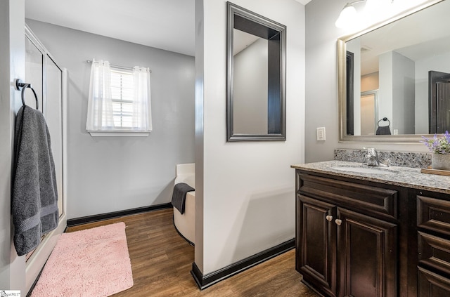 full bath with baseboards, wood finished floors, and vanity