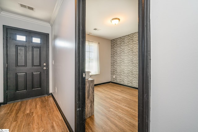 entrance foyer featuring wood finished floors, visible vents, and crown molding