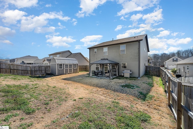 rear view of property with a gazebo, a shed, an outdoor structure, and a fenced backyard