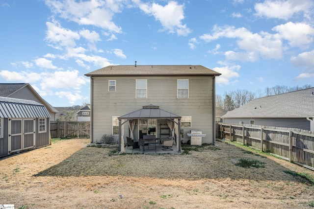 rear view of house with a storage unit, a gazebo, a patio area, a fenced backyard, and an outdoor structure