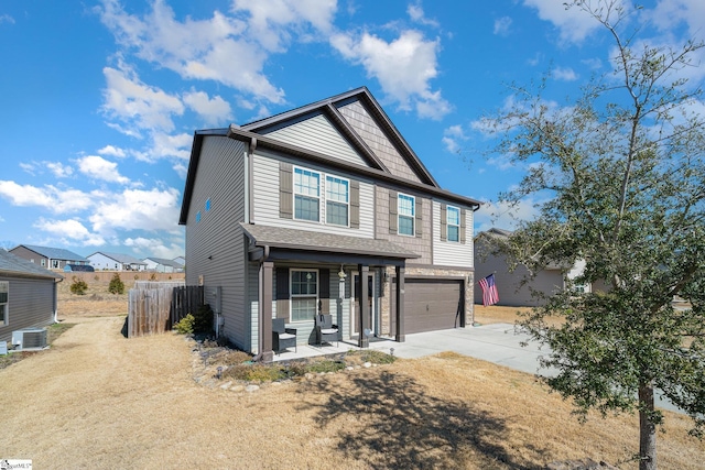 view of front of property featuring an attached garage, covered porch, central AC, fence, and concrete driveway