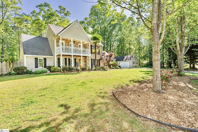 view of front of property featuring a balcony, fence, stone siding, roof with shingles, and a front lawn