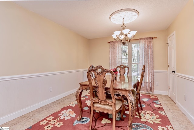 dining area featuring a chandelier, a textured ceiling, light tile patterned flooring, and baseboards