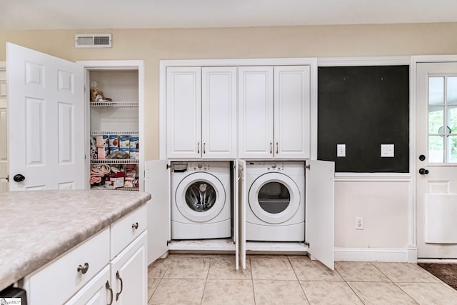 washroom featuring light tile patterned floors, cabinet space, visible vents, and washer and dryer