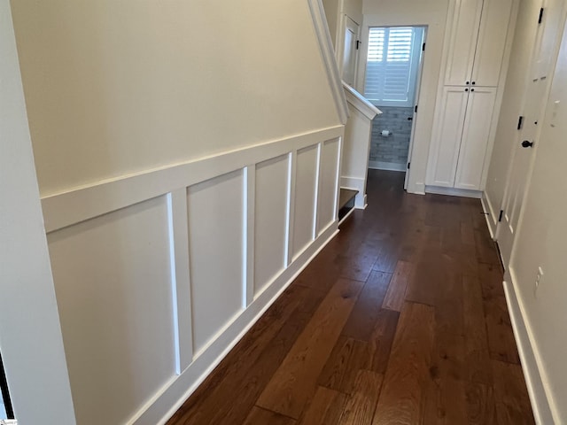 hall featuring dark wood-type flooring and a decorative wall