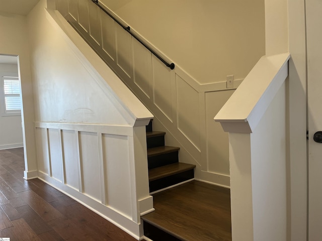 stairway featuring baseboards, wood finished floors, and a decorative wall