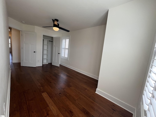 unfurnished bedroom with a closet, dark wood-style flooring, baseboards, and a ceiling fan