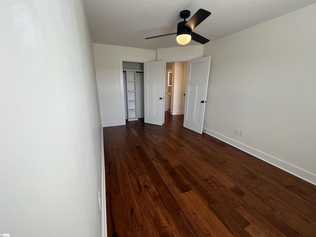 unfurnished bedroom with a ceiling fan, a closet, baseboards, and dark wood-style flooring