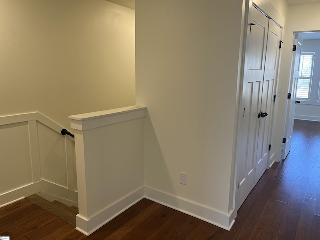 corridor featuring baseboards, dark wood finished floors, and an upstairs landing